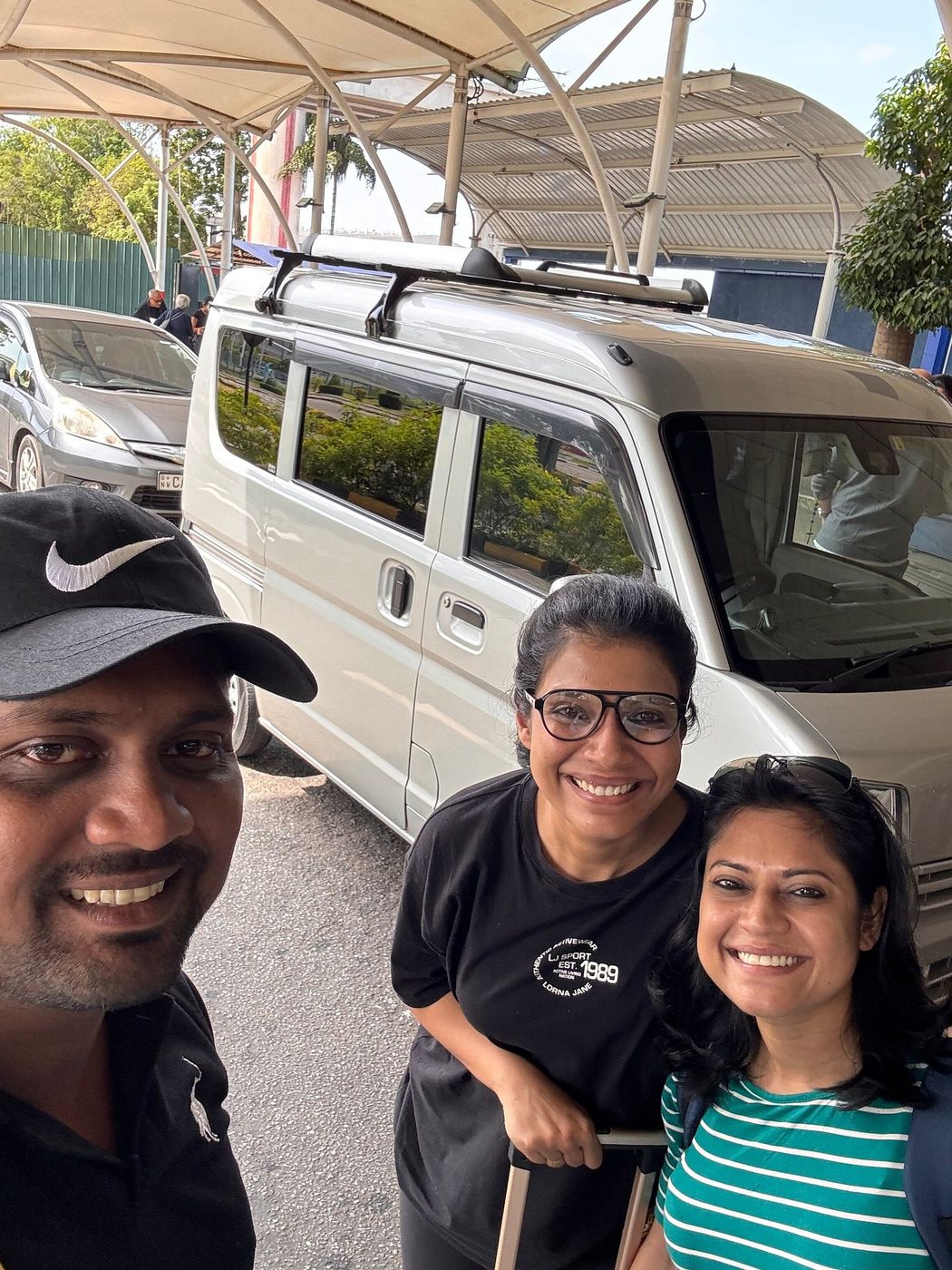 Nipuna with two guests in front of the white tour van