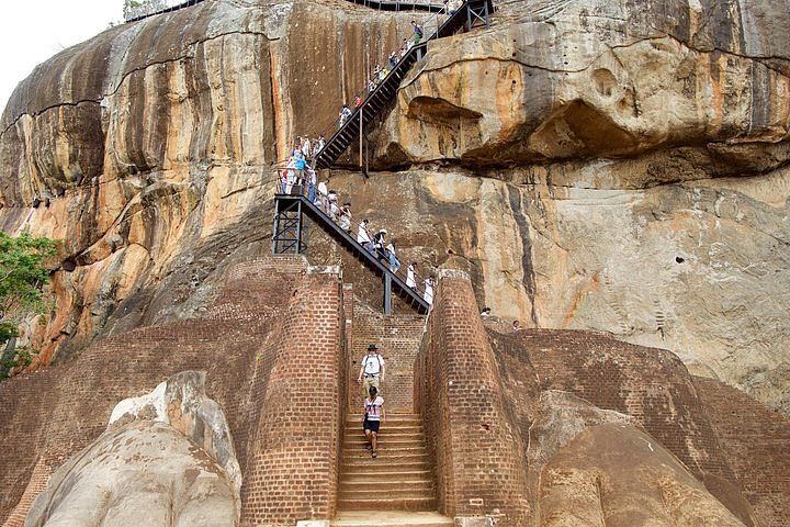 Visitors climbing the stairs cut into Sigiriya rock